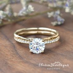 a close up of a diamond ring on a wooden surface with flowers in the background