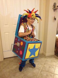 a young boy dressed up as a clown holding a cardboard box with his head in the shape of a star