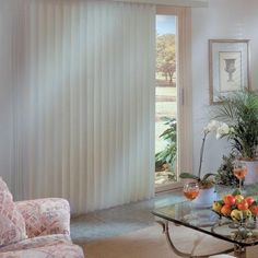 a living room filled with furniture next to a window covered in sheer curtains and flowers