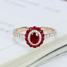 a red and white diamond ring sitting on top of a book