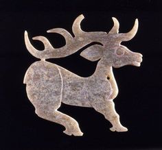 an animal made out of stone sitting on top of a black surface with two horns