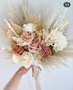 a hand holding a bouquet with flowers and feathers