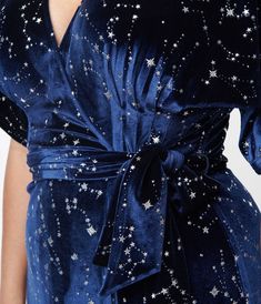 Wrap yourself in stars, dears! This sensational 1970s style wrap dress from Unique Vintage is crafted in a gorgeous navy blue velvet that dances with twinkling silver stars throughout. The sultry wrap design is secured with dual buttons creating a surplice neckline that is framed by dolman sleeves. The seamed high waist is cinched by a matching self tie sash while the skirt cascades to a sweeping midi silhouette!Available in sizes XS-5X while supplies last. Holiday Cocktail Dress Plus Size, Blue 1920s Dress, 70s Dresses Formal, Feyre Dress, Dune Fashion, Celestial Gown, Dark Blue Velvet Dress, Fashion Definition, Starry Dress