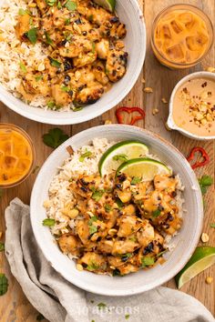 two white bowls filled with chicken and rice next to orange sauce on a wooden table