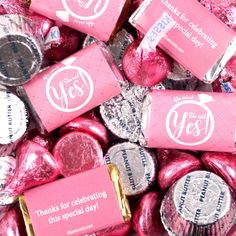 pink and silver candies with the words yes written on them are surrounded by foil wrappers