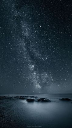 the night sky is filled with stars and some rocks in front of it, as well as