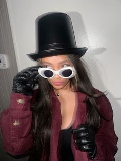 a woman in a top hat and gloves with goggles on her face, wearing black gloves