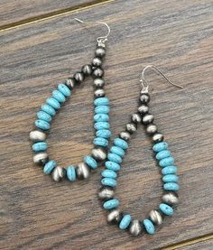 two pairs of turquoise and silver beaded earrings sitting on top of a wooden table