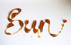 the word sun is made out of melted chocolate and caramel colored liquid on a white surface