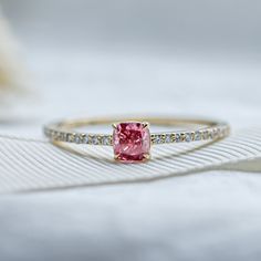 a pink diamond ring sitting on top of a white cloth covered tablecloth with diamonds around it