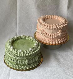 two cakes sitting next to each other on top of a white cloth covered tablecloth