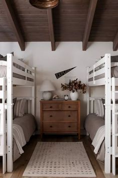 two white bunk beds sitting next to each other on top of a wooden dresser in a bedroom