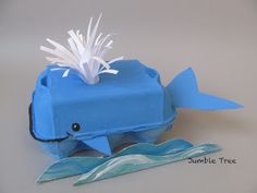 an origami model of a blue whale with white feathers