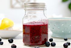 a glass jar filled with blueberries next to some lemons