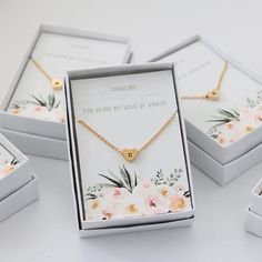 three personalized necklaces in boxes with flowers on them and one gold heart pendant