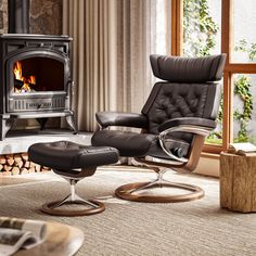 a living room with a chair, ottoman and fire place