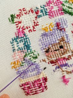 a close up of a person working on a cross stitch project