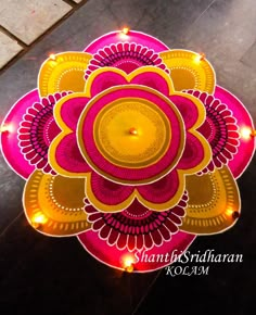 a lit up pink and yellow flower on top of a black floor with lights around it