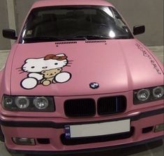 a pink car with a hello kitty sticker on the hood