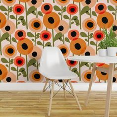 two chairs and a table in front of a wall with an orange flower pattern on it