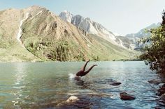 a person swimming in a lake with mountains in the background