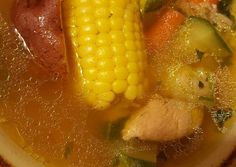 corn on the cob soup with carrots and other vegetables in it, ready to be eaten