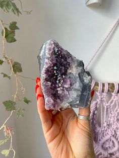 a woman holding up a rock with purple crystals on it