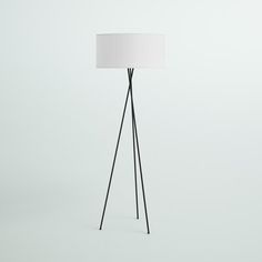 a black tripod floor lamp with a white shade