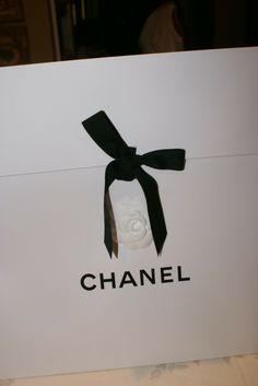 a white box with a black ribbon on the side and a flower in the middle