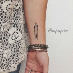 a woman's arm with a tattoo on it and two bracelets around her wrist