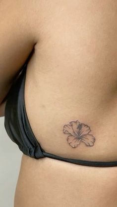 a woman's stomach with a flower tattoo on the side of her belly,