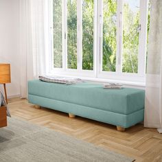 a blue bench sitting in front of a window next to a bed with pillows on it