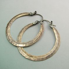 "The ultimate large bronze and sterling silver hoop earrings. Our new bronze ( also known as red brass and nugold ) Rio design, meticulously and deftly forged for a polished but rustic look. Finished with our sterling silver latch design for a secure and easy to use closure that maintains a sleek profile. A dynamic pair of handmade hammered hoops that are sure to become a favorite addition to your jewelry collection. Oxidized, brushed and polished to finish. Rio Hoops are a signature Mocahete de Elegant Brass Hoop Earrings With Oxidized Finish, Elegant Oxidized Brass Hoop Earrings, Bronze Hammered Sterling Silver Jewelry, Hammered Bronze Metal Jewelry, Small Bronze Metal Hoop Earrings, Handmade Bronze Hoop Jewelry, Bronze Hoop Earrings For Jewelry Making, Artisan Electroformed Hoop Earrings, Bronze Metal Hoop Jewelry