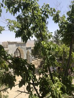 an old stone building is seen through the trees in this view from behind some branches