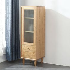 a tall wooden cabinet sitting in front of a window next to a blue drapes