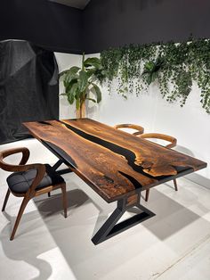 a wooden table sitting next to a chair on top of a white floor covered in plants