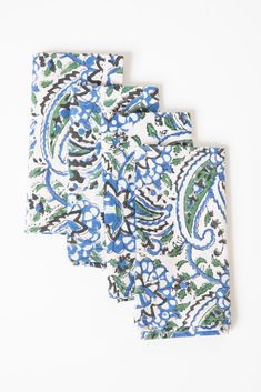 three blue and green paisley napkins on a white surface with one folded in the middle