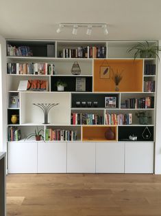 a living room filled with lots of books on top of white shelving unit units