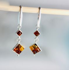 This moderne  long pair of silver earrings featuring genuine Baltic Amber of mix color.Elegant style is perfect for daily or evening wear. Material : Genuine Baltic Amber /sterling Silver925/1000e Color : green ,honey red ,lemon Dimensions : 47 x 14 mm Finish : Polished Please note, colors might vary due to computer setting ,and lightening . All our product handcrafted , manually processing. Luxury Amber Jewelry With Accent Stones, Cheap Bohemian Amber Jewelry, Earrings Square, Amber Earrings, Women Earrings, Amber Stone, Amber Jewelry, Square Earrings, Earrings Long