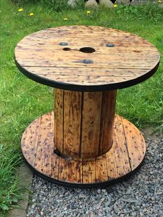 a wooden spool sitting on top of a green grass covered field next to rocks