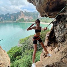 a woman climbing up the side of a cliff