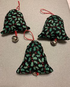 three bells with holly print on them sitting on a table