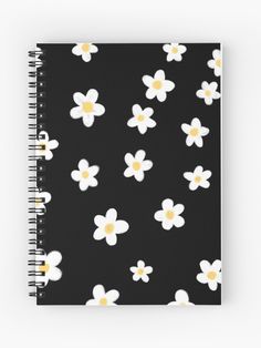 a spiral notebook with white and yellow flowers on black, featuring small daisies in the center