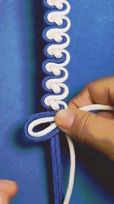 a person is tying a blue and white cord to a piece of fabric that has the word facebook written on it