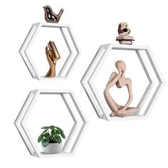 three hexagonal shelves with different sculptures on top of each one and a potted plant in the middle