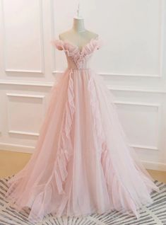 Enveloped in the tender hue of a blooming rose, this prom dress is a vision of delicate allure. The bodice, with its sculpted off-shoulder sleeves and artful ruching, is a masterpiece of texture and form. Subtle floral embellishments, meticulously placed, add a dimension of understated elegance. The full skirt, a cascade of soft tulle, lends an air of balletic grace, ensuring that each step is as enchanting as the last. This gown is for the prom-goer who wears her heart on her sleeve and desires a dress that speaks softly but resonates deeply. Prom Dress Pink, Prom Dresses Off The Shoulder, Tulle Long Prom Dress, Pink Evening Dress, A Line Evening Dress, Pink Wedding Dress, Tulle Evening Dress, Floor Length Prom Dresses, Pink Prom Dress