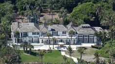 an aerial view of a large white house surrounded by palm trees