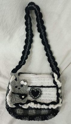 a crocheted purse with a cat on the front and black trimmings