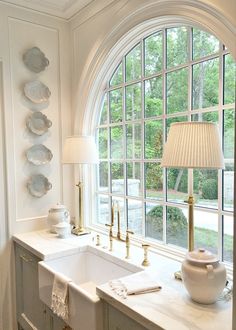 a kitchen with an arched window, sink and lamp on the counter next to it