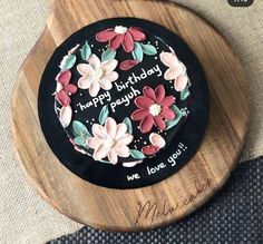 a birthday cake with flowers on it sitting on a wooden plate